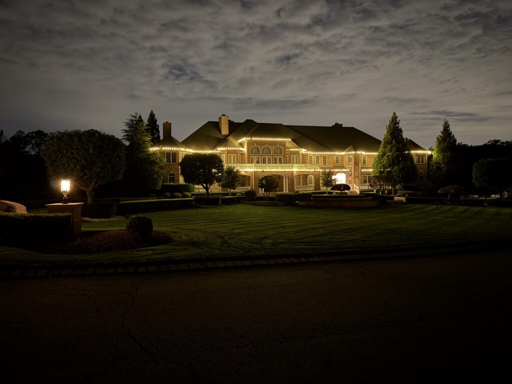 Large estate with a warm white roofline under a cloudy dusk sky