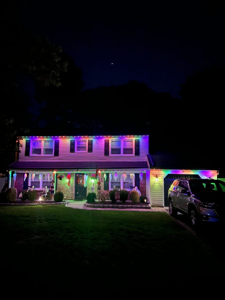 House with a purple and multicolor permanent roofline at night