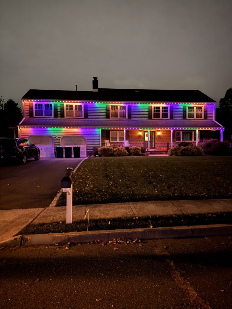 Two-story house with a rainbow permanent roofline at dusk
