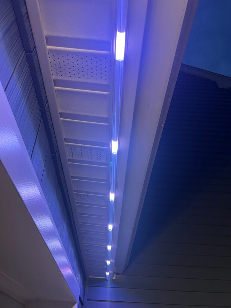 Close-up of the slim permanent light track under the eave, lit blue